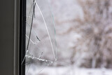 Fototapeta  - Szklane ostre odłamki tkwiące w ramie okiennej . Widok przez wybite okno na drzewa przyprószone śniegiem .