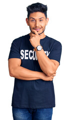 Sticker - Handsome latin american young man wearing security t shirt looking confident at the camera smiling with crossed arms and hand raised on chin. thinking positive.