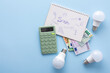 © pundapanda - Save energy, accounting and saving money, energy saving light bulbs and notebook on a blue background, money spending planning, rising electricity costs, energy crisis in Europe