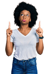 Poster - Young african american woman wearing casual white t shirt pointing up looking sad and upset, indicating direction with fingers, unhappy and depressed.