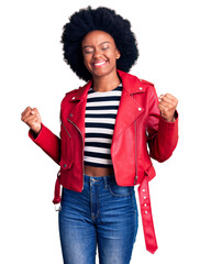 Poster - Young african american woman wearing red leather jacket very happy and excited doing winner gesture with arms raised, smiling and screaming for success. celebration concept.