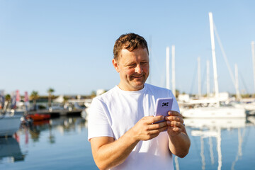 A man communicates on the phone against the background of yachts and a marina