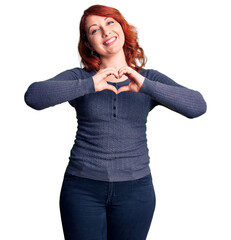 Sticker - Young beautiful redhead woman wearing casual t-shirt smiling in love showing heart symbol and shape with hands. romantic concept.