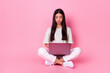 © deagreez - Full size portrait of pretty nice indonesian girl sit floor use wireless netbook isolated on pink color background