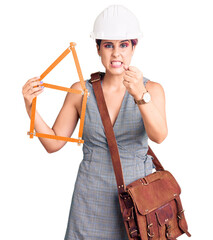 Canvas Print - Young beautiful woman wearing architect hardhat holding build project annoyed and frustrated shouting with anger, yelling crazy with anger and hand raised