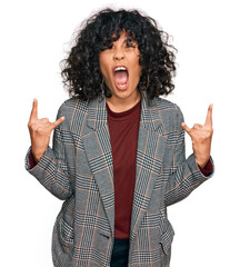 Poster - Young hispanic woman wearing business clothes shouting with crazy expression doing rock symbol with hands up. music star. heavy concept.