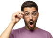 © Damir Khabirov - Studio portrait of young man dressed in pink t-shirt, holding glasses looking with round open mouth with surprise
