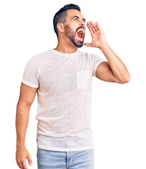 Poster - Young hispanic man wearing casual clothes shouting and screaming loud to side with hand on mouth. communication concept.