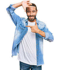 Wall Mural - Attractive man with long hair and beard wearing casual denim jacket smiling making frame with hands and fingers with happy face. creativity and photography concept.