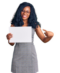 Beautiful african american woman holding blank empty banner smiling happy pointing with hand and finger