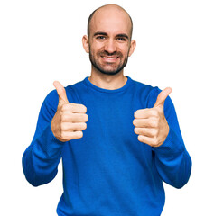 Wall Mural - Young hispanic man wearing casual clothes approving doing positive gesture with hand, thumbs up smiling and happy for success. winner gesture.