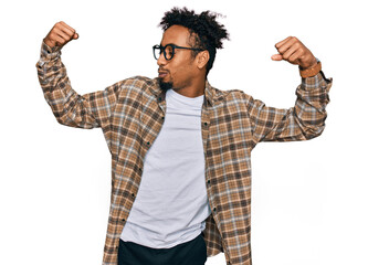 Young african american man with beard wearing casual clothes and glasses showing arms muscles smiling proud. fitness concept.