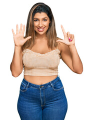 Poster - Beautiful brunette woman wearing casual clothes showing and pointing up with fingers number seven while smiling confident and happy.