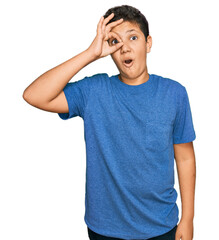 Wall Mural - Teenager hispanic boy wearing casual clothes doing ok gesture shocked with surprised face, eye looking through fingers. unbelieving expression.