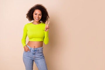 portrait of young cute smiling girl wear yellow top showing v-sign party photosession isolated on be