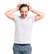 © Krakenimages.com - Middle age handsome man wearing casual t-shirt posing funny and crazy with fingers on head as bunny ears, smiling cheerful