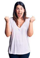 Poster - Young beautiful brunette woman wearing casual t-shirt celebrating surprised and amazed for success with arms raised and open eyes. winner concept.