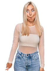 Wall Mural - Young blonde woman wearing casual clothes making fish face with lips, crazy and comical gesture. funny expression.