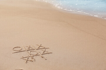 Poster - Tic tac toe game drawn on sand near sea, space for text