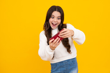 Poster - Excited teenager child holding cellphone. Close-up portrait of cute teen girl using mobile phone, cell web app, isolated over bright vivid vibrant yellow color background.