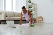 Man Sports, Watching Tape Of Workout On Phone And Repeating Exercises Sports Blogger With Laptop Training Online, Pumped Up Man Fitness Trainer Works Out At Home, The Concept Of Health And Body Beauty