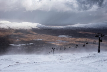 Wall Mural - Epic Winter landscape image from mountain top in Scottish Highlands down towards Rannoch Moor during snow storm and spindrift off mountain top in high winds