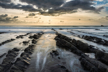 Wall Mural - Beautiful sunset landscape image of Welcome Mouth Beach in Devon England with beautiful rock formations