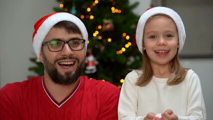 Wall Mural - Happy family, father and little daughter throw snow on background of shining Christmas tree at home and laugh. New year and christmas