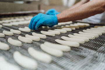 Wall Mural - Huge factory line for sweet food and cookies production. Close up shots of worker's hand with protective glove doing some selection and product arranging.