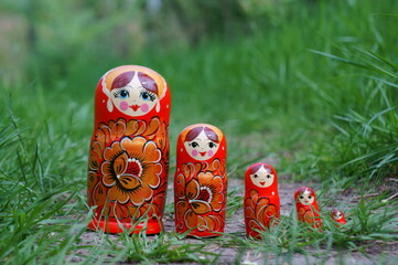 Sticker - A row of nesting dolls in close-up against a background of green foliage. Slavic culture.