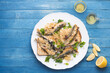 © uliab - Marinated  sardines or Sarde in saor, a typical dish from the Venice, Italy  with white onions marinated with wine vinegar, raisins and pine nuts, served with bread. Blue marine wooden table. Copy spa