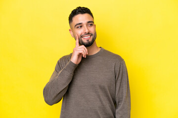 Wall Mural - Young Arab handsome man isolated on yellow background thinking an idea while looking up