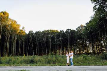 Happy family in a park in summer autumn. Mother, father and baby play in nature in the rays of sunset