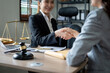 © Natee Meepian - Gavel Justice hammer on wooden table with judge and client shaking hands after adviced in background at courtroom, lawyer service concept.