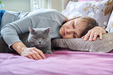 Middle Aged Woman Sleeping With Cat On Bed