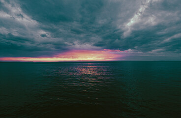 Poster - Sunset over the Beagle Channel in Argentina.  Image Has a sliver of sunlight due to the storm clouds, and there is a faint silhouette of land. 