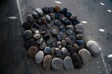 Beach Stones In A Mandala With Scattered Light Pattern.  