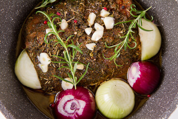 Sticker - Raw pork loin seasoned - ready to be roasted, in a pot with onions and garlic