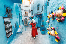 Young Woman With Red Dress Visiting The Blue City Chefchaouen, Marocco - Happy Tourist Walking In Moroccan City Street - Travel And Vacation Lifestyle Concept