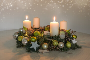 Second Advent, wreath with two burning white candles and green Christmas decoration on a table, home decor for the first Sunday, copy space, selected focus