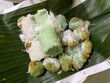 This is Klepon and Putu which means snack of sweet rice cake balls filled with molten palm sugar and coated in grated coconut placed on banana leaf.