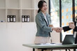 © NanSan - Female business worker with colleagues in Thailand working together at office desk, getting shaking hands, successful and agreement concept