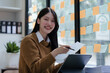 © NanSan - Cheerful asian businesswoman wearing sweater working at workplace female office worker during working day in office, smile and looking camera