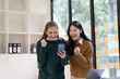 © NanSan - Cheerful asian business woman wearing sweater with colleagues working together at workplace female office worker during working day in office, looking mobile