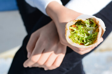 Woman holding delicious vegetable roll outdoors, closeup