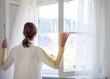 canvas print picture - Frau steht am weit geöffneten Fenster und blickt nach draußen - Lüftungskonzept