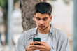 © carballo - young millennial student looking at mobile phone on the street
