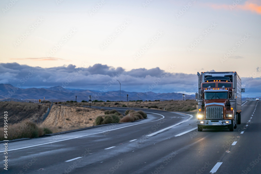 Brown classic big rig semi truck tractor with turned on headlight ...