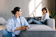 © F8  \ Suport Ukraine - Young man and woman sitting together on couch while using laptop and smartphone