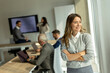 © BGStock72 - Young business woman at startup office with arms crossed in front of her colleagues as team leader